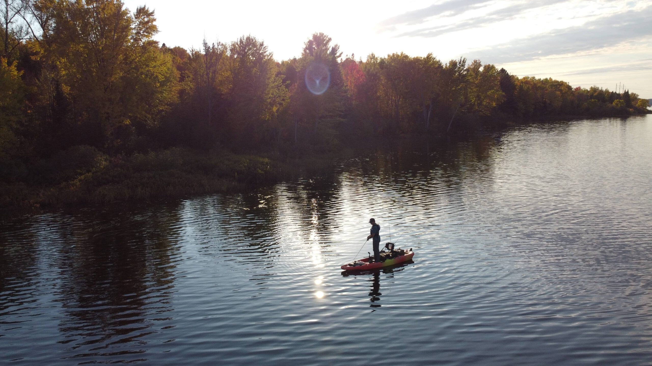 A single person standing on a small boat, fishing