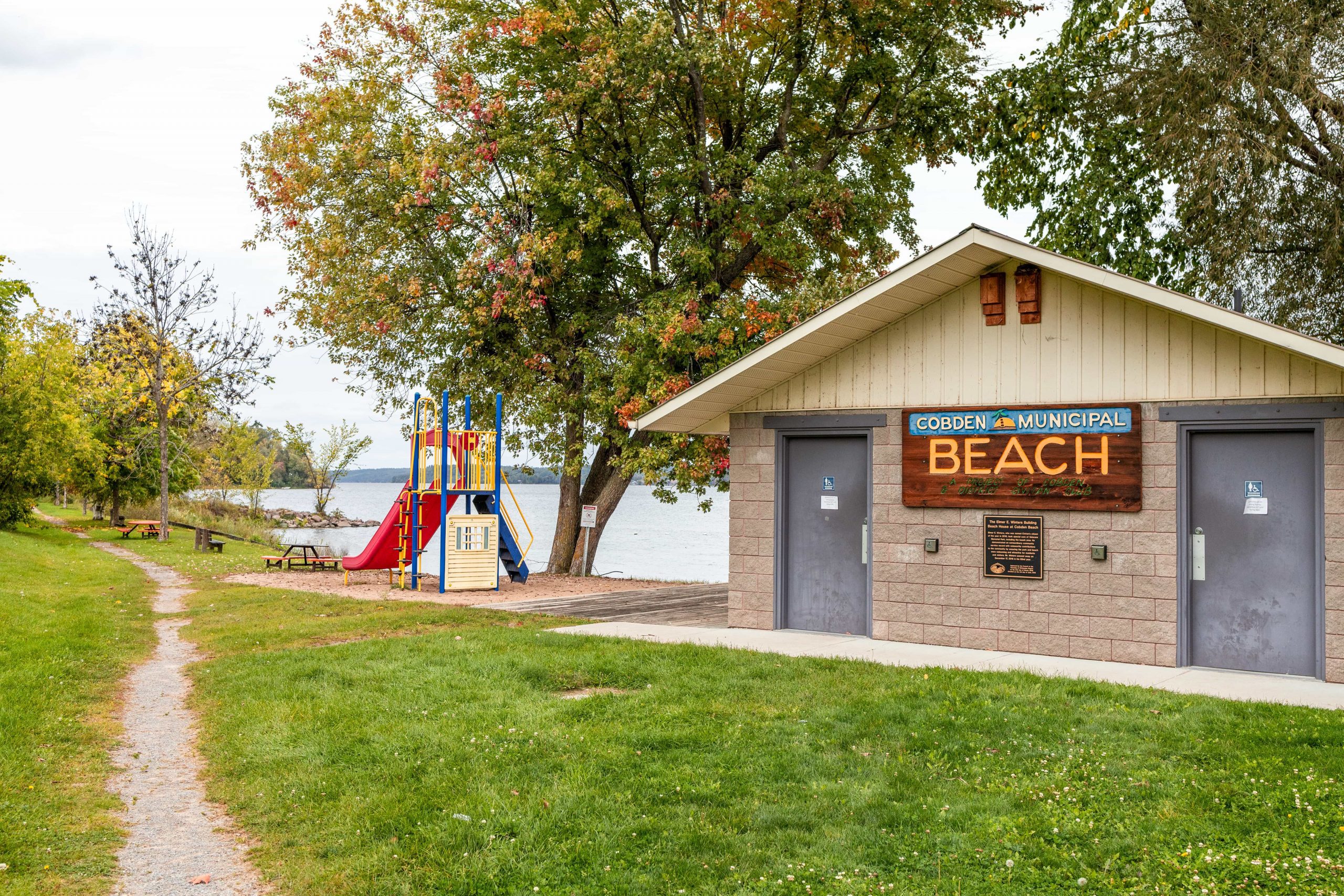 Cobden beach building and sign, beside a play park and a path