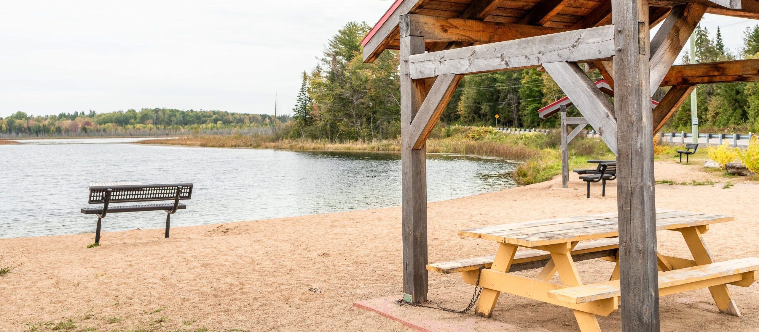 A picnic table under shelter and a bench at Little lakes beach
